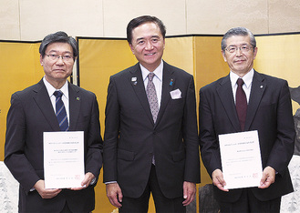 黒岩知事から手渡された選定書を持つ山下純正総長（右）と野田政樹院長（左）
