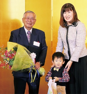 花束を贈呈され笑顔の梶会長(左)