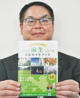 新しいガイドブックを手にする事務局長の鈴木昭弘さん