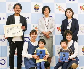 山田代表（左上）と絵本をもらった園児たち