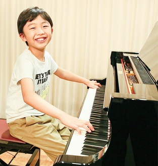 ピアノを前に笑顔を見せる石崎さん
