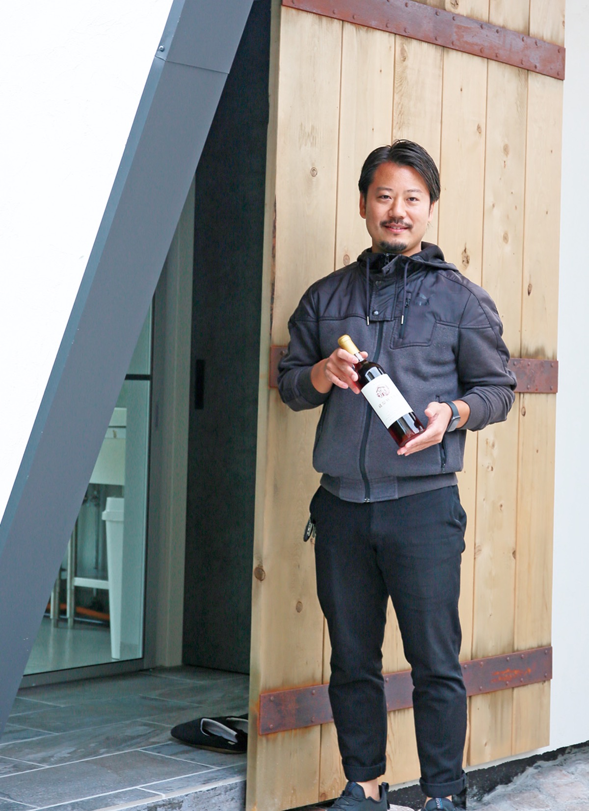 岡上に建設中の醸造所を前に立つ山田さん