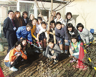 植えた河津桜を囲む６年生の児童と川崎さくらライオンズクラブのメンバー