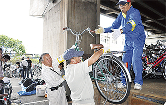 解体した自転車をトラックに乗せる市民