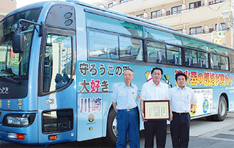 寄贈されたデザインシートを纏ったバス（左から福井消防局長、工藤理事長、関貴光専務）