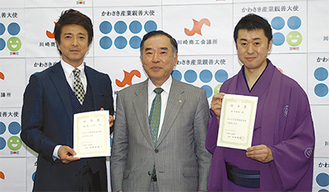 大使に任命された米多朗さん（右）と風間さん（左）。中央は山田会頭