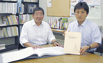 決算カードを開く江井理事長（左）と白書を手にする村松秀幸事務局長