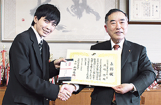 表彰状を贈った浦崎さんと握手を交わす山田会頭（左から）