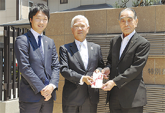 寺尾理事長（右）に寄付金を手渡す石川弘行社長（中央）と純一郎取締役