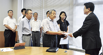 伊藤副市長（右）に申し入れ書を手渡す市民ネットワークのメンバー