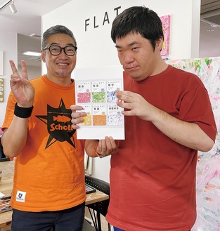 テキストのデザインを手にする宮本さん（右）と大平理事長＝同スタジオ提供
