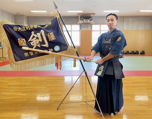 優勝旗の前で竹刀を持つ遠藤さん