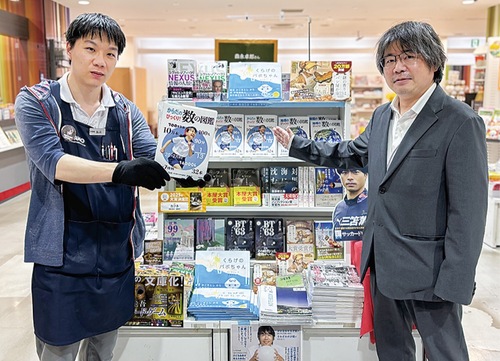 図鑑を手にする書店販売員＝北野書店