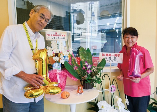 リスナーなどから届いた花の前に立つ清水代表（左）と成美さん