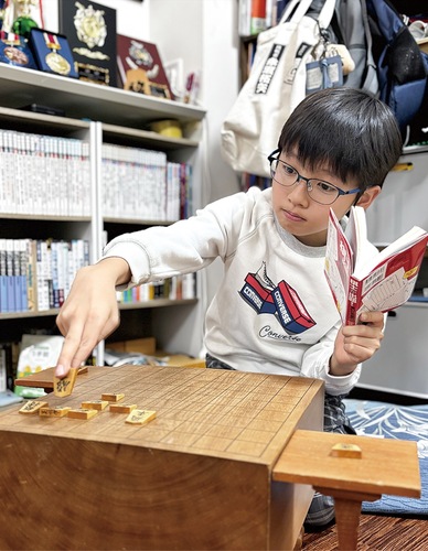 本を手に詰将棋を行う黒松さん
