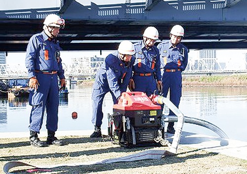 可搬ポンプで多摩川から取水する団員ら