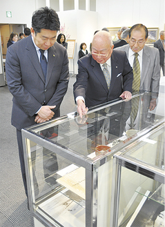 福田市長（左）に展示品を説明する斎藤委員長（中央）