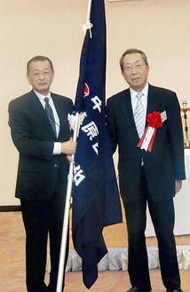 贈呈された支部旗を手にする佐々木会長（左）