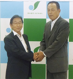締結式で握手をかわす田所会長（左）と加山俊夫市長