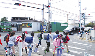 信号機が設置された丁字路交差点の横断歩道を渡り、下校する児童＝９日、同所