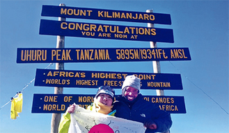 キリマンジャロの山頂でガイドとともに日の丸を掲げる齋藤さん