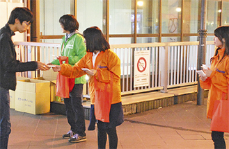 オレンジリボンを配布する学生＝11日、橋本駅
