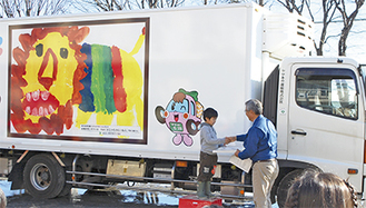 自身の作品が描かれたトラックの前で表彰される笠原さん