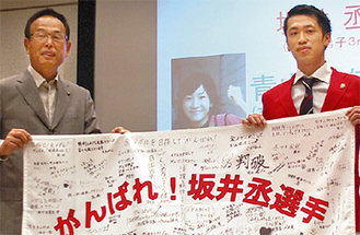 加山俊夫市長とともに応援メッセージを手にする坂井選手（右）＝７月22日壮行会