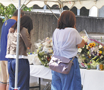 犠牲者を悼み、献花の前で手を合わせる人々＝7月31日