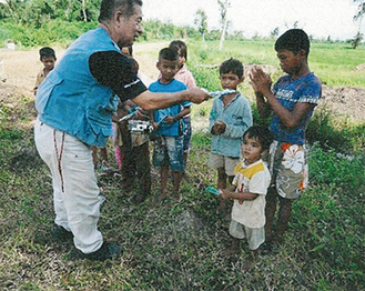 地雷や不発弾の情報を提供してくれたカンボジアの子どもたちへ歯ブラシを手渡す伊藤さん（写真は提供）