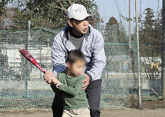 児童にボールの打ち方を指導する篠塚さん＝提供写真