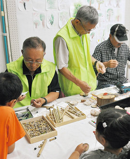 木材を使ったおもちゃの作り方を教える地元団体のメンバーと子どもたち