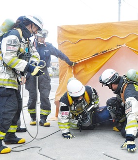 救助隊員の指導のもと実際に使用されている防火衣を着装して救助体験を行う参加者ら＝24日、北消防署相原分署