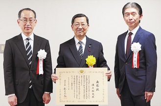 表彰状を手に笑顔の浦上さん（中央）と良峰徴収部長（左）、山本署長（右）