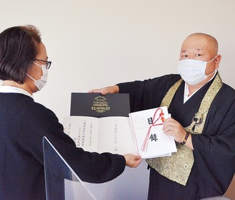 宮崎ＲＣ会長（右）から目録を受け取る事務局スタッフ