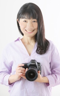 カメラを手に笑顔の小松さん