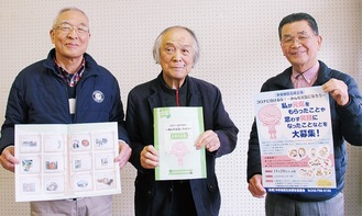 完成した作品集や、応募に使用したポスターを見せる（左から）プロジェクトリーダーの鳥海さん、中央地区社協の徳田会長、小林副会長
