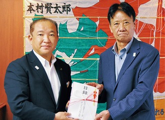目録を本村賢太郎市長（左）に手渡す三塚会長