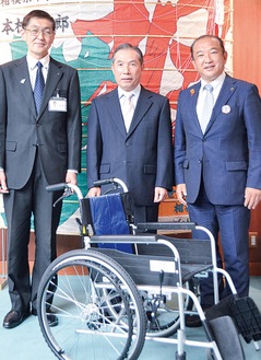 寄贈の車椅子を前に笑顔の大沼社長（中央）と笹野会長（左）、本村市長＝10日、市庁舎
