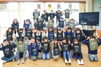 完成したバッグを手にとびきりの笑顔を見せる5年1組のメンバー＝2日、富士見小学校