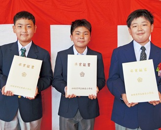 バナナペーパーの卒業証書を手に笑顔の卒業生＝23日、田名小学校