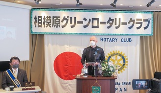 例会で卓話するデニスさん（中央）。左は長谷川会長＝3月、クラブ提供
