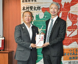 本村市長に寄付金の目録を手渡す齊藤会長（右）