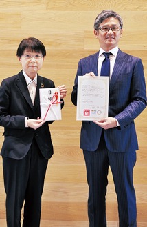 贈呈式の様子。目録を受け取った渡邉志寿代教育長（左）とお礼状を受け取った津谷代表理事