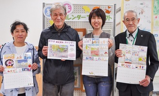 完成したカレンダーを手に笑顔の長谷川会長（右）と実行委員会のメンバー