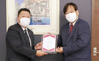 伊藤典範の籾浦誠一さん（左）から寄付を受け取る井戸代表理事
