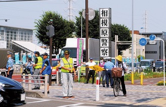 警察署前で交通指導する協会員ら（18日）