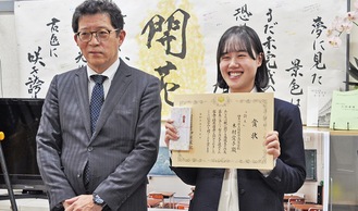 賞状を受け取り笑顔の木村さん（右）。作文は自ら税務署へ届けたという。左は伊熊署長