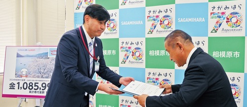 寄付金目録を市長に手渡す久保西神奈川事業部長