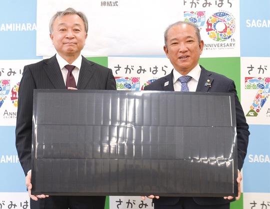 締結式で太陽電池を持つ栗谷川代表取締役社長（左）と本村市長
